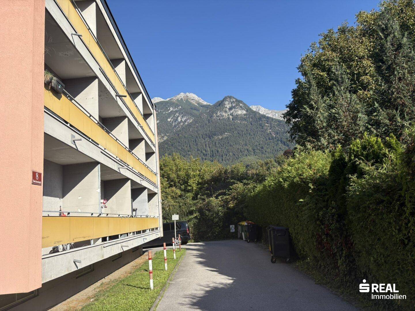 Gebäudefassade mit Balkonen und einem beeindruckenden Blick auf die umliegende Berglandschaft.