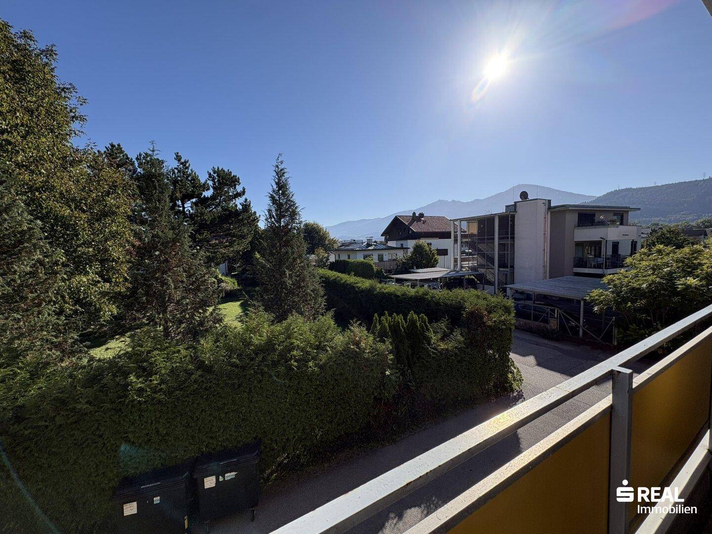 Weiter Blick vom Balkon über die Dächer der Nachbarschaft bis zu den fernen Bergen.