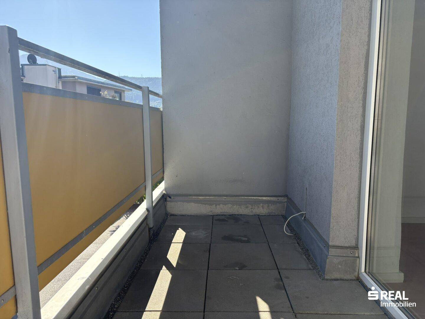 Leerer Balkon mit Fliesenboden und Metallgeländer, bereit zur individuellen Gestaltung.