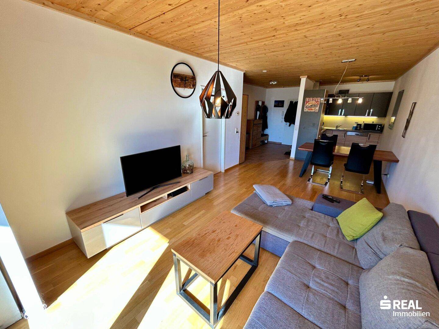 Heller Wohn- und Essbereich mit Holzbalkendecke, Parkettboden und moderner Einrichtung.