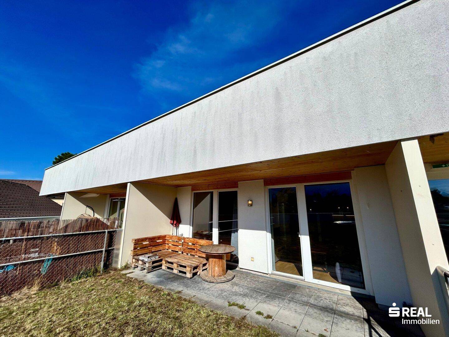 Terrasse mit Holzmöbeln und Zugang zum Gartenbereich.