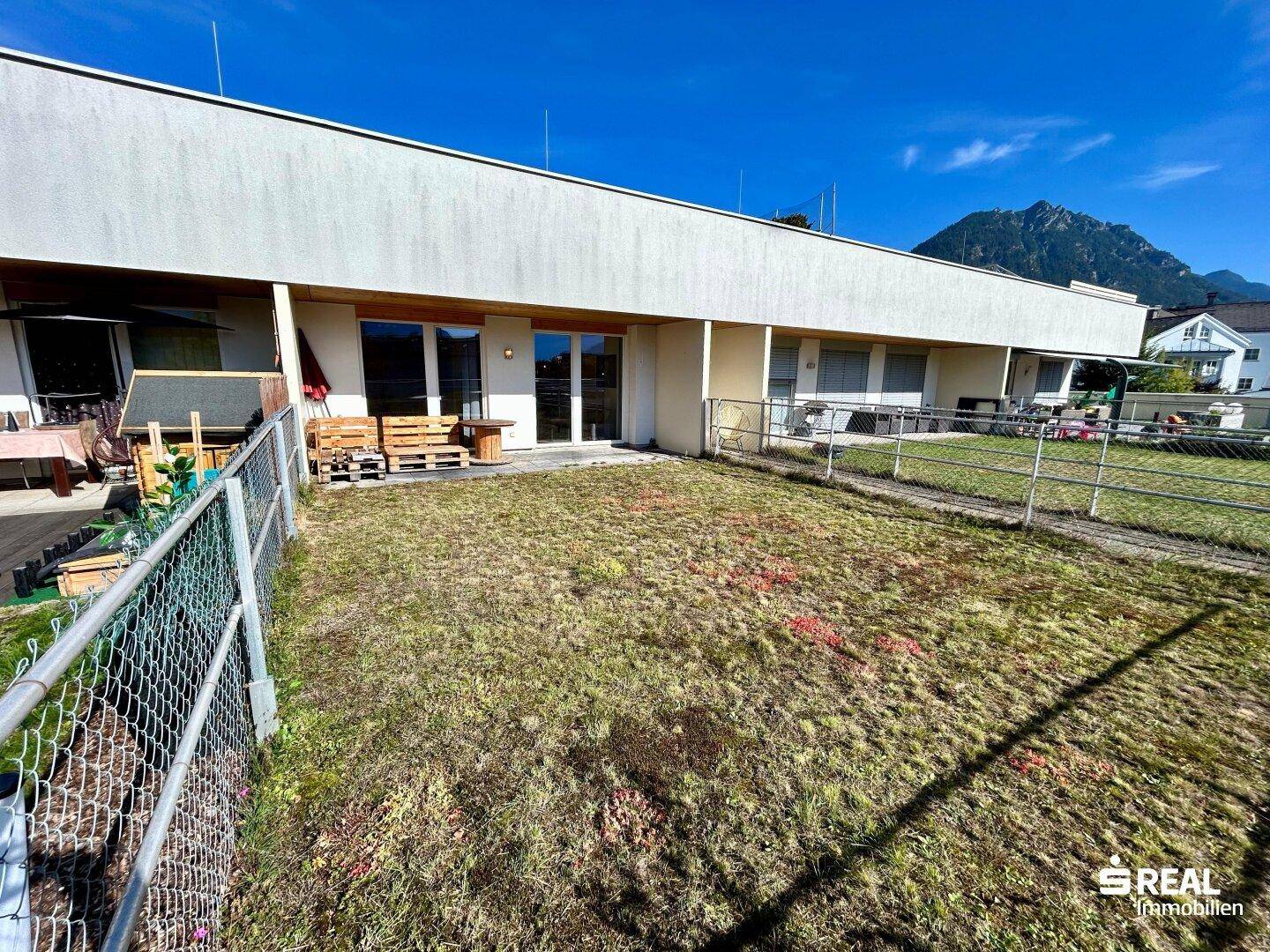 Großer Gartenbereich mit Rasenfläche, Terrasse und Bergblick im Hintergrund.
