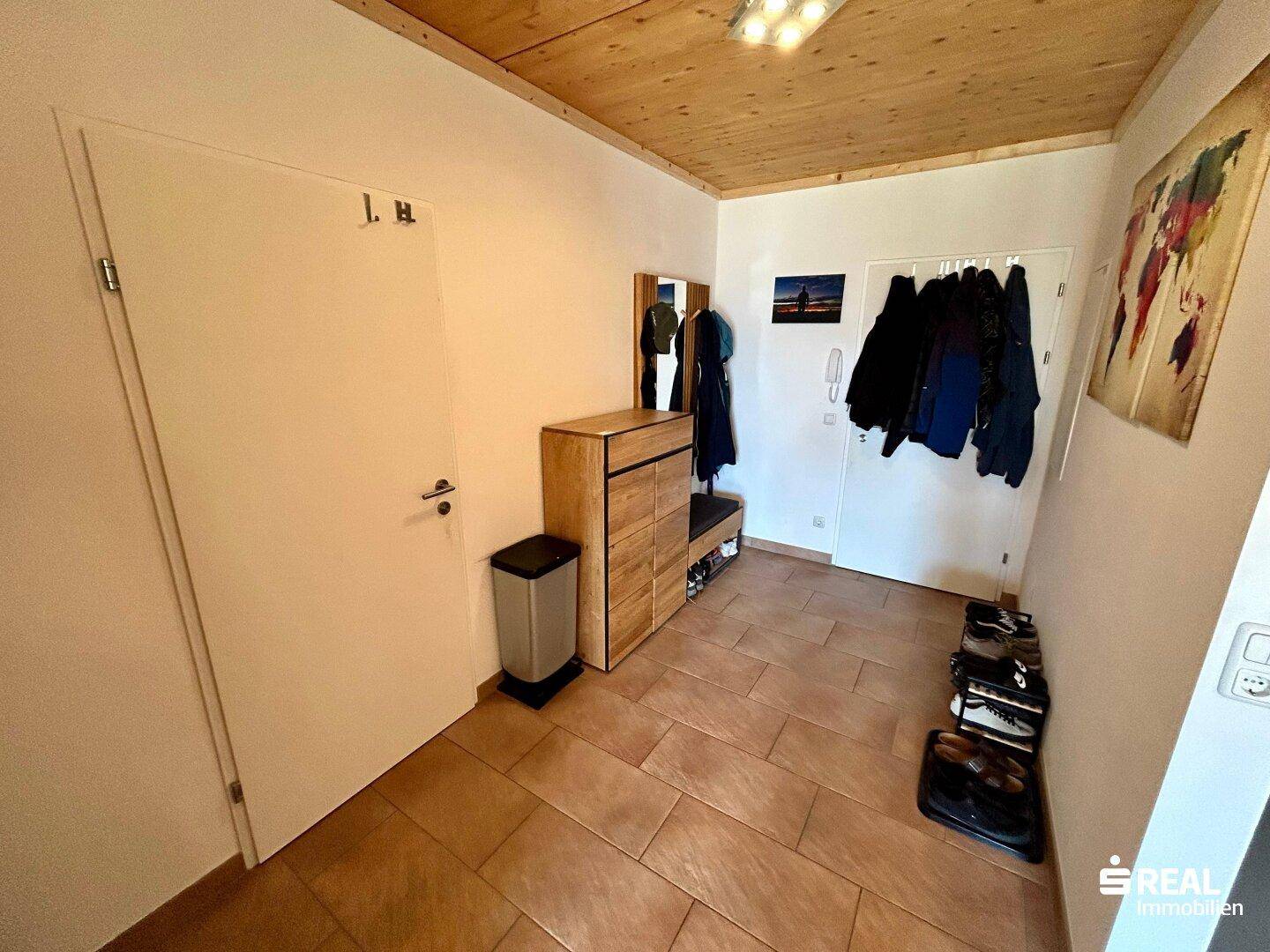 Eingangsbereich mit Fliesenboden, Garderobe und Holzmöbeln.