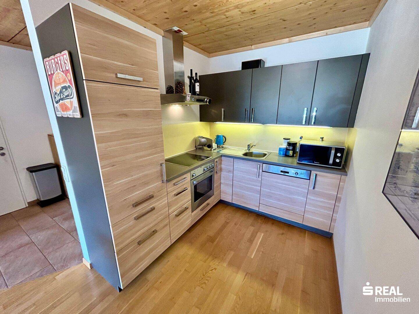 Moderne Einbauküche mit Holzfronten, dunklen Oberschränken und integrierten Geräten.