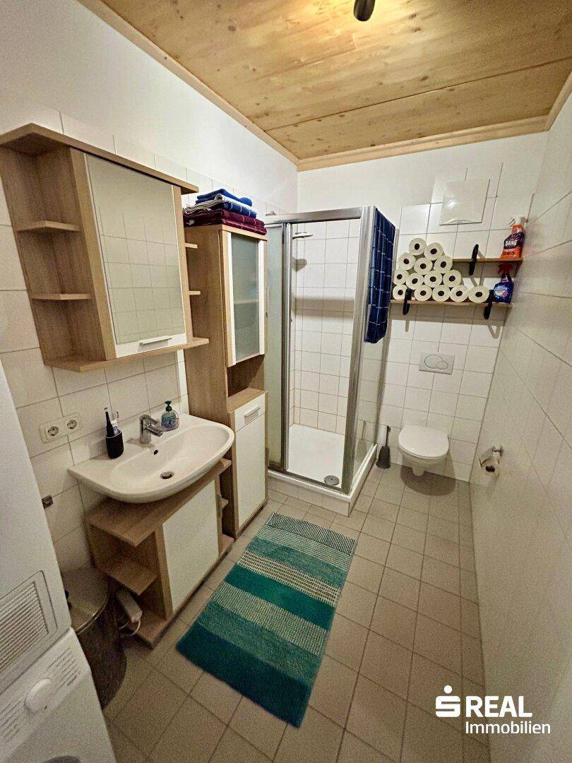 Badezimmer mit Dusche, WC, Waschbecken und Spiegelschrank.