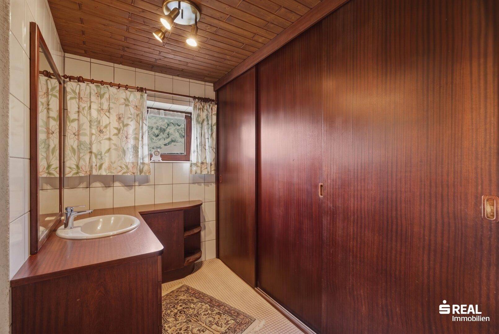 Badezimmer mit Holzwaschtisch, Spiegelschrank und großen Schiebetüren.