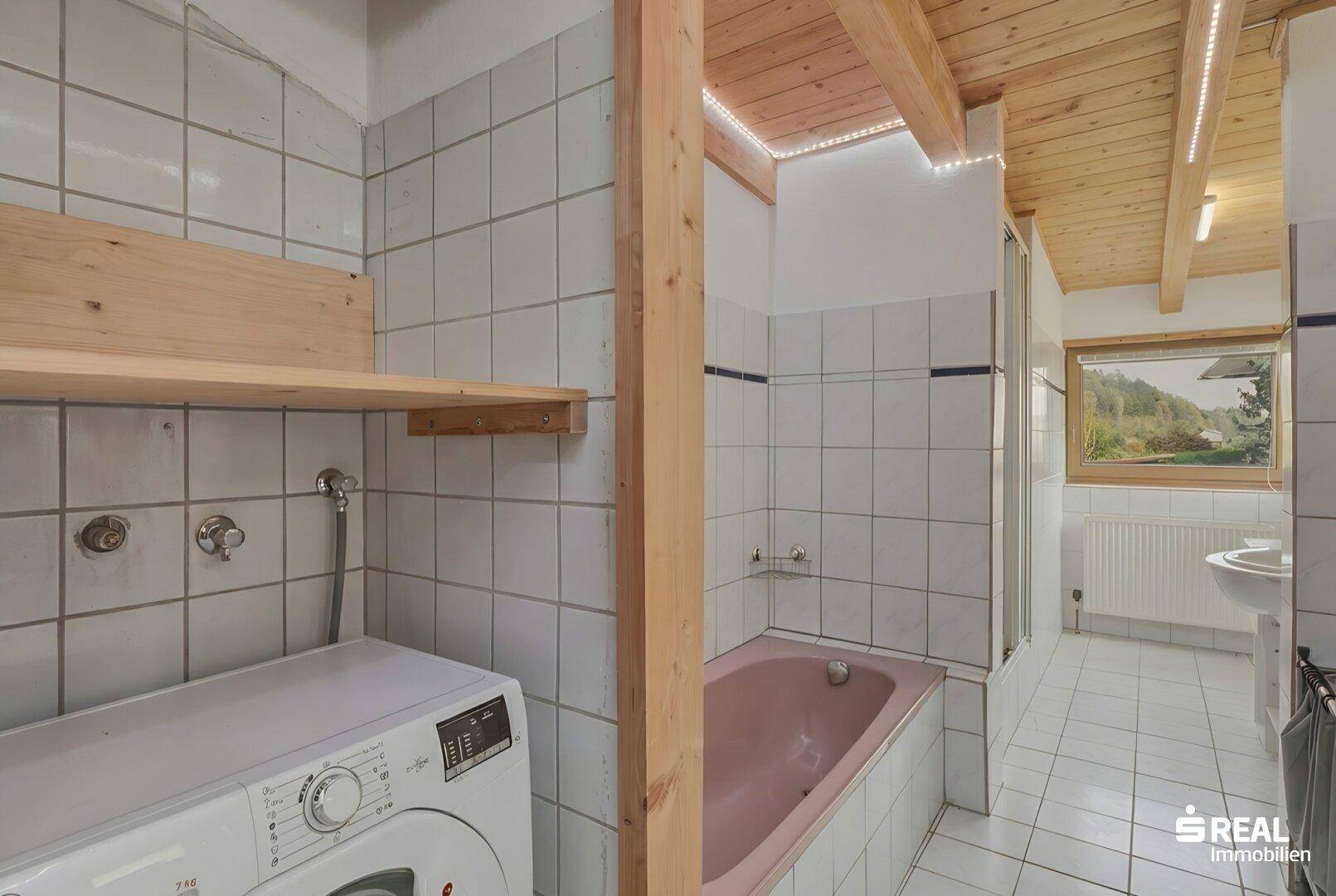 Badezimmer mit rosa Badewanne, Dusche, Waschmaschine und Holzdecke.