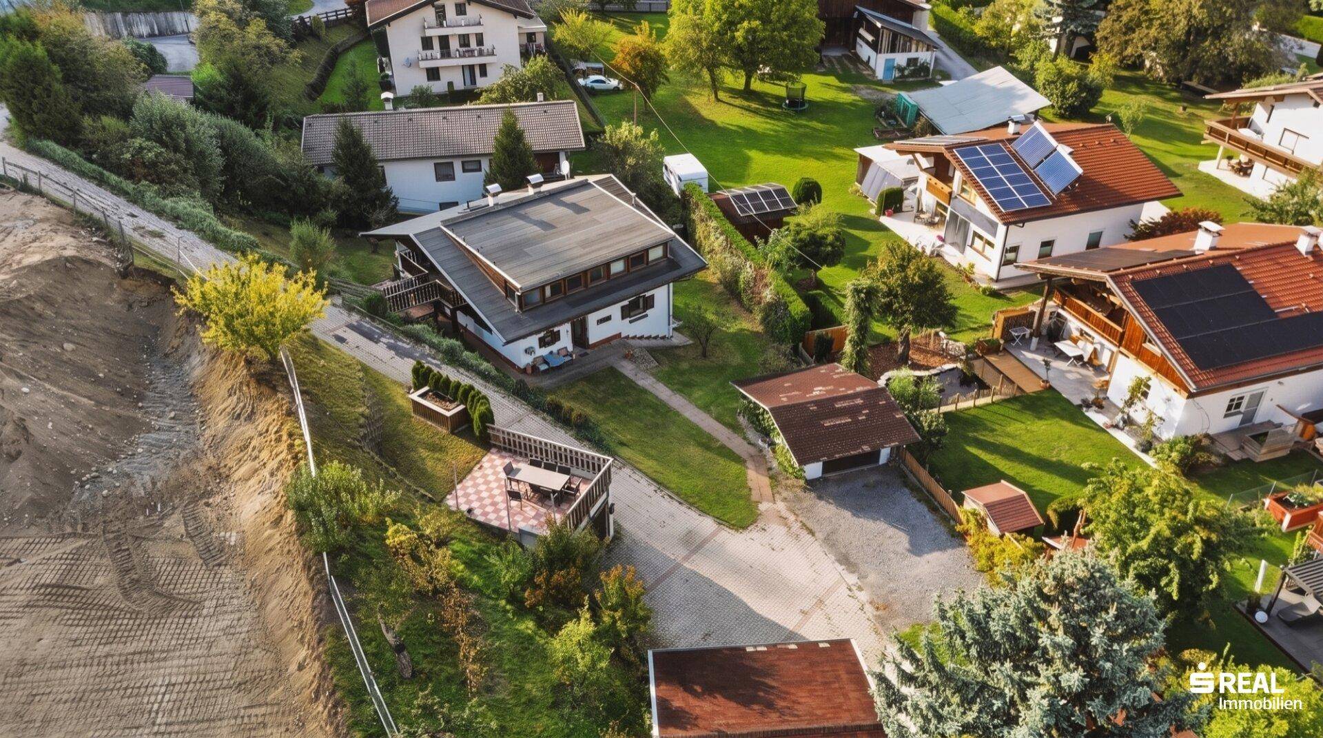Schräge Luftaufnahme des Hauses mit umliegender Bebauung und viel Grün.