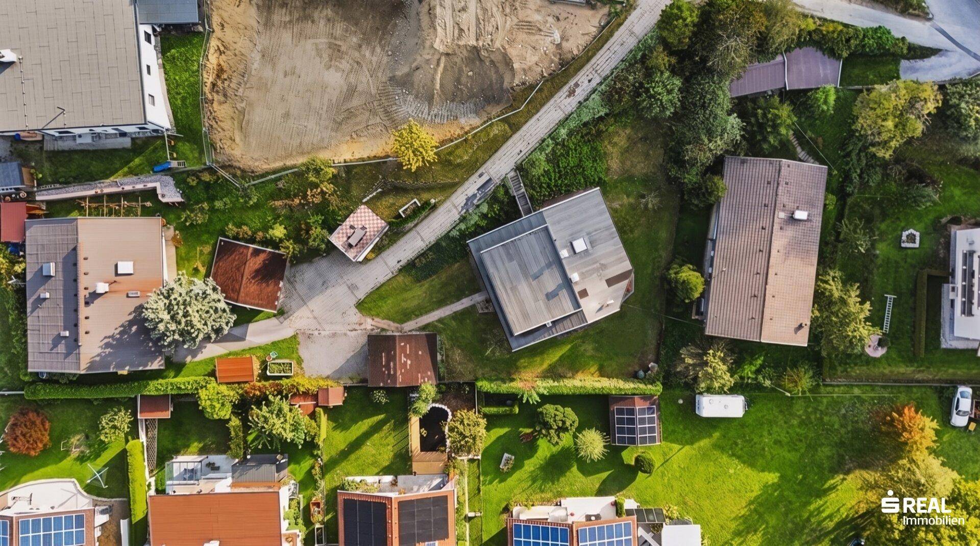 Vogelperspektive des Grundstücks mit angrenzenden Häusern und viel Grünfläche.
