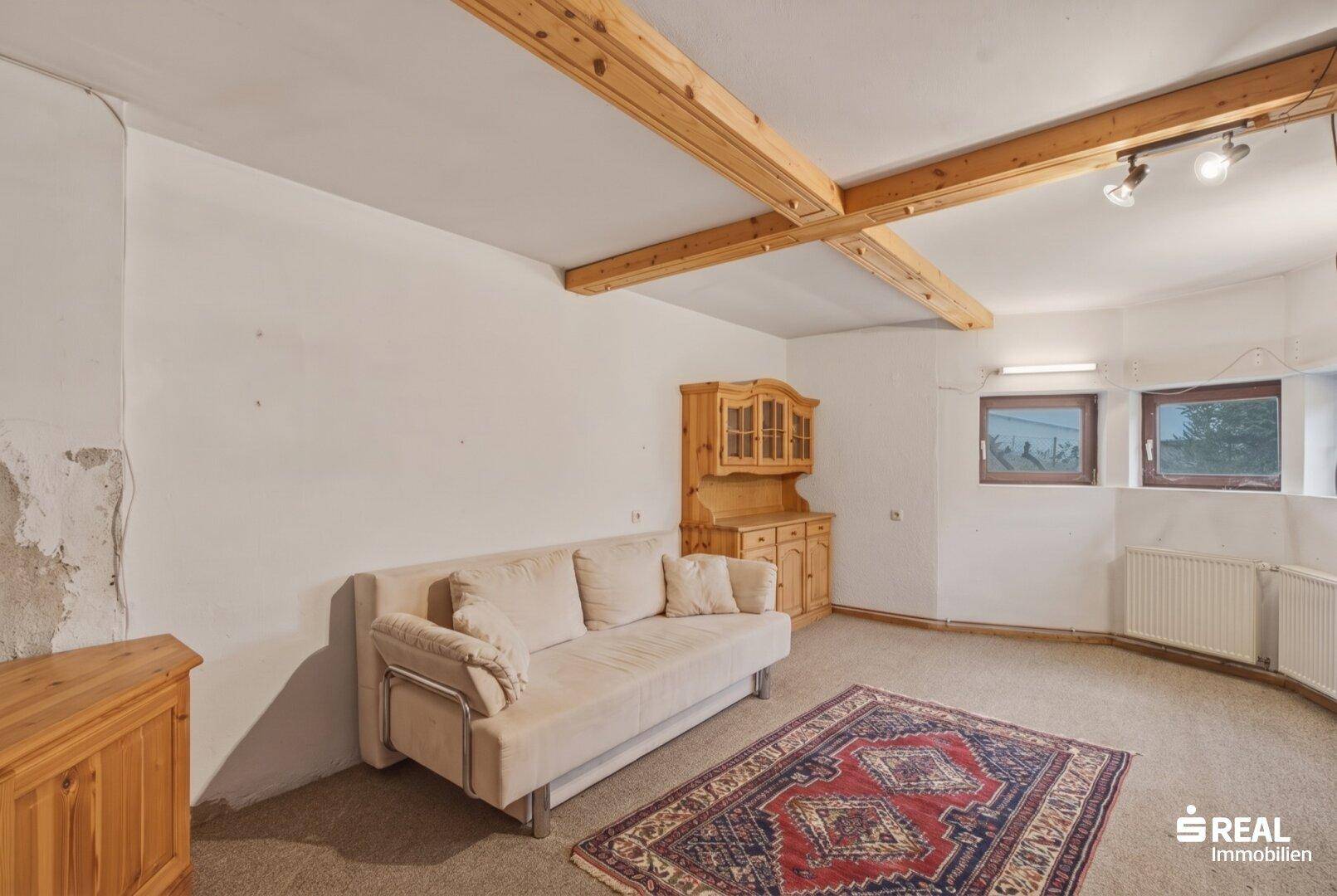 Kellerraum mit Teppichboden, Holzbalken und kleinem Fenster, als Gästezimmer nutzbar.
