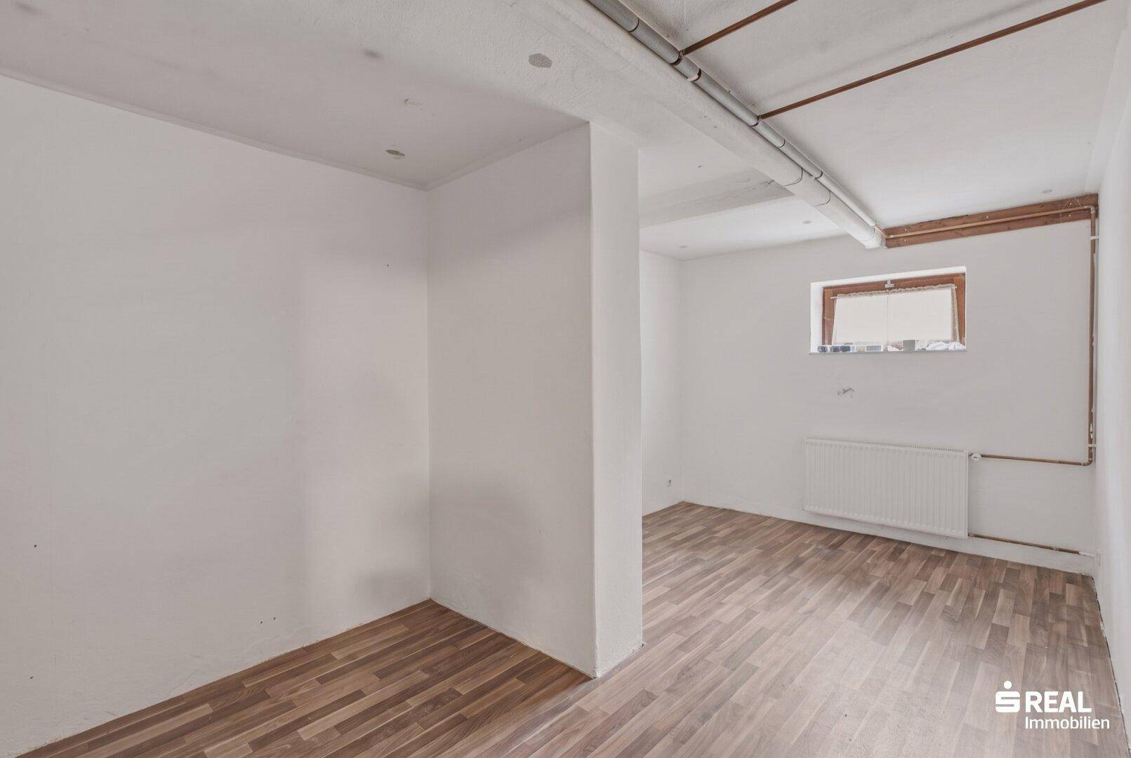 Renovierter Kellerraum mit Laminatboden und Heizkörper, vielseitig nutzbar.