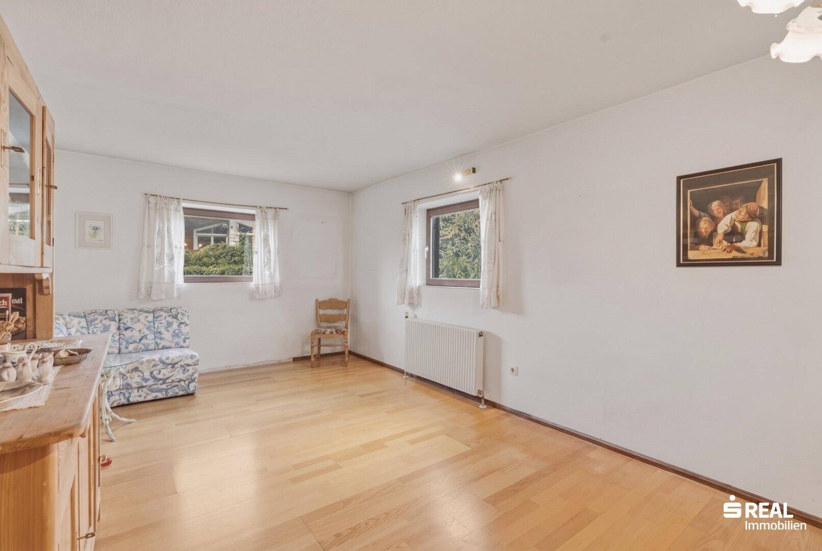 Geräumiges Zimmer mit Parkettboden, großen Fenstern und traditionellem Holzschrank.
