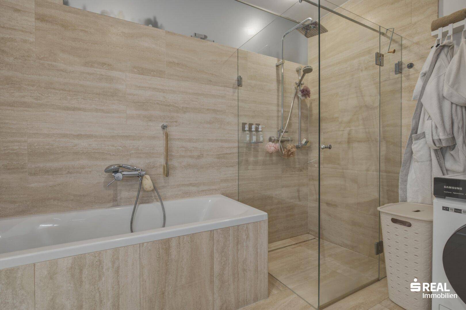 Modernes Badezimmer mit Badewanne, begehbarer Dusche und beigefarbenen Fliesen.