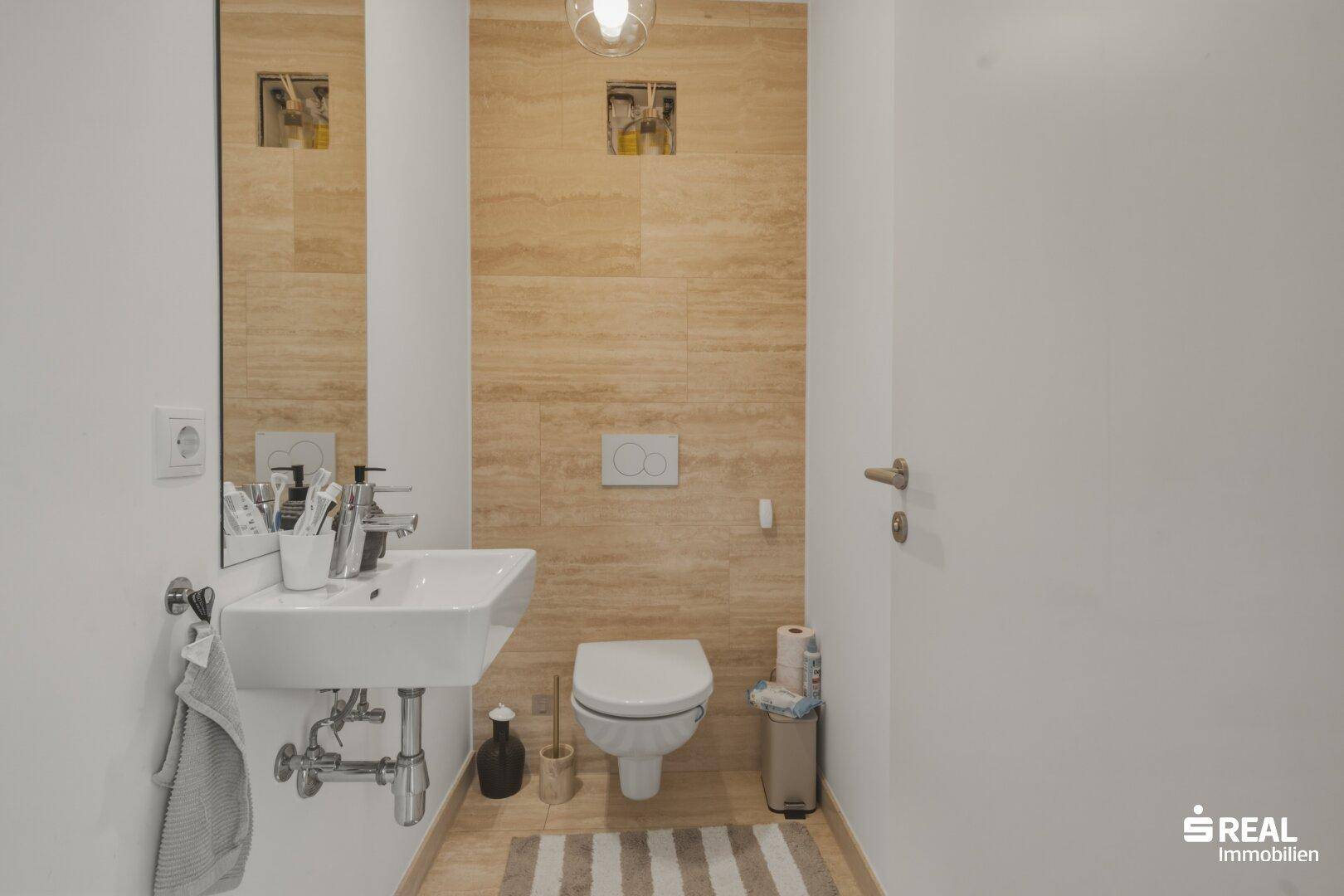 Kleines Gäste-WC mit modernem Waschbecken, Wand-WC und beigefarbenen Fliesen.