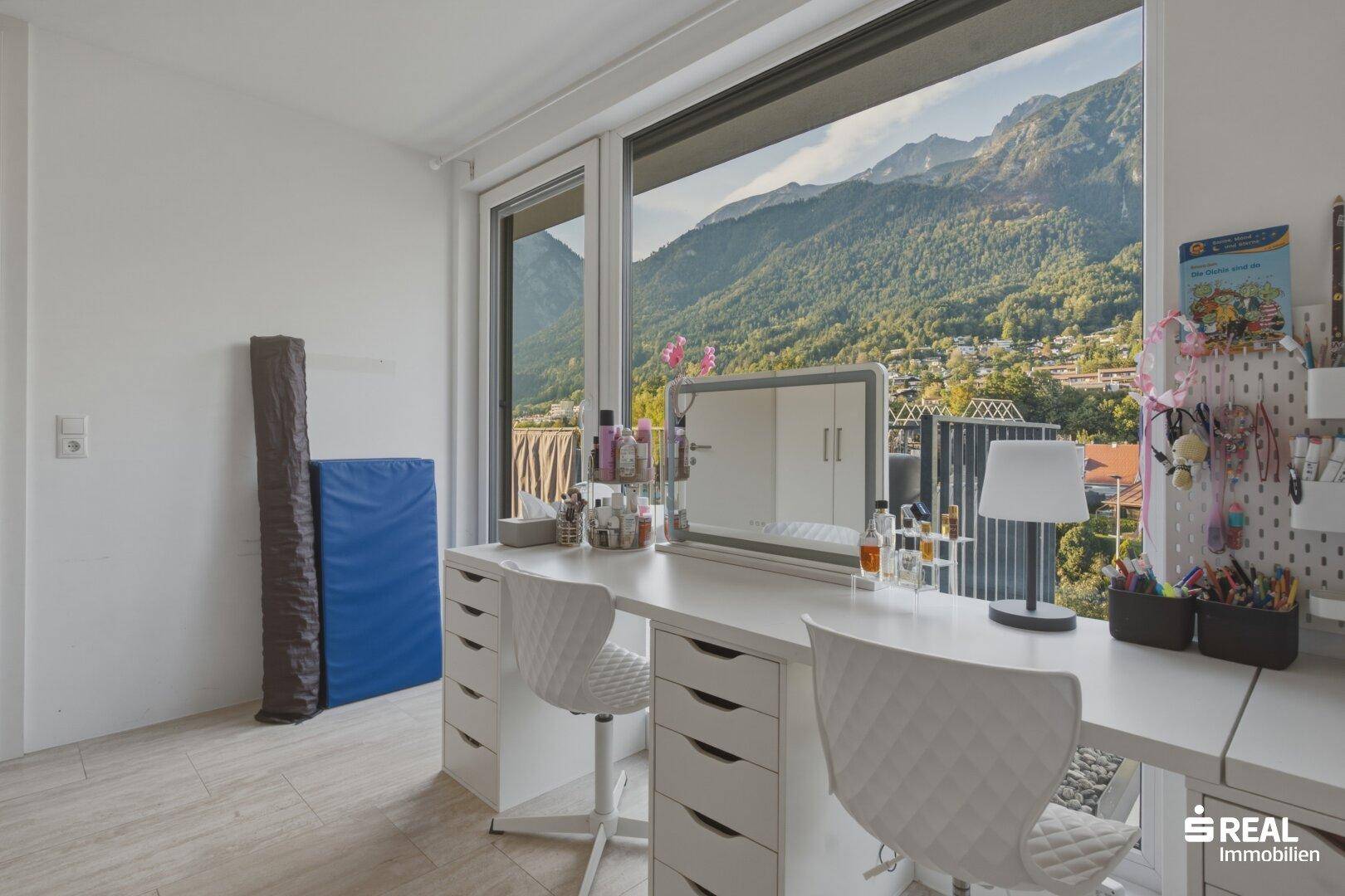 Helles Zimmer mit großem Fenster, Bergblick und einem geräumigen Schminktisch mit Stühlen.