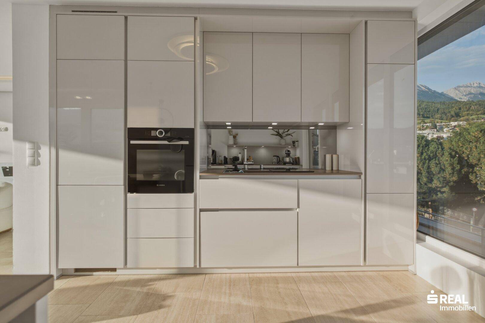 Elegante, moderne Einbauküche mit glänzenden Fronten, integriertem Backofen und viel Stauraum.