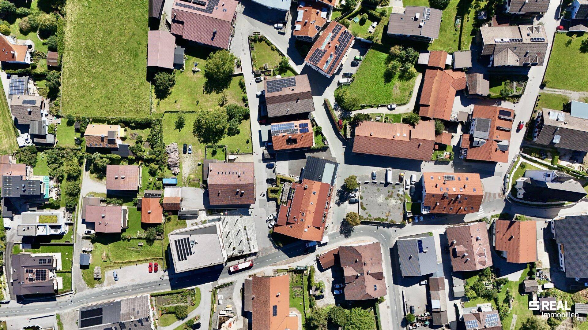 Senkrechte Luftaufnahme einer Wohnsiedlung mit verschiedenen Häusern, Straßen und Grünflächen.