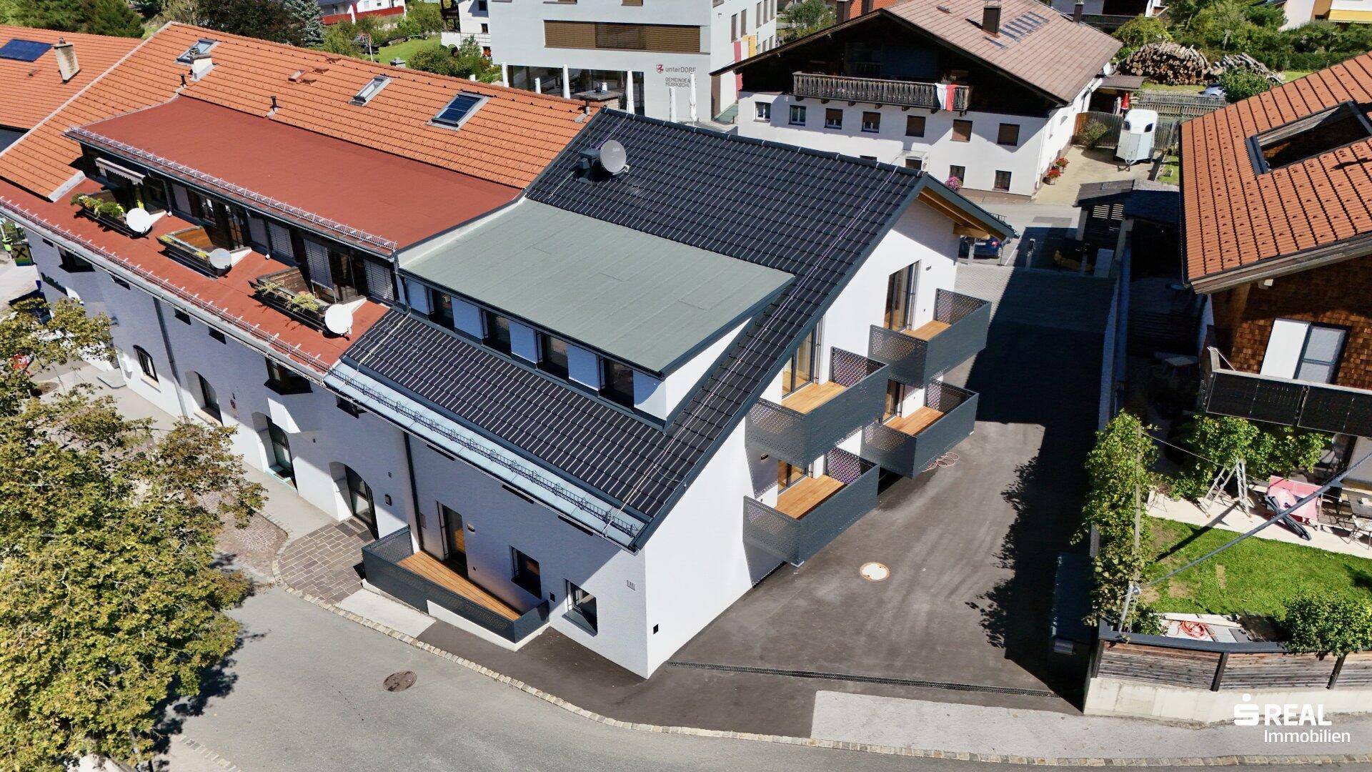 Modernes Mehrfamilienhaus mit mehreren Balkonen und zeitgenössischer Architektur neben einem älteren Gebäude.