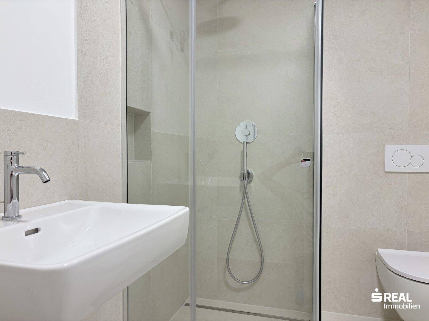 Modernes Badezimmer mit begehbarer Dusche, wandhängendem WC und eleganten grauen Fliesen.
