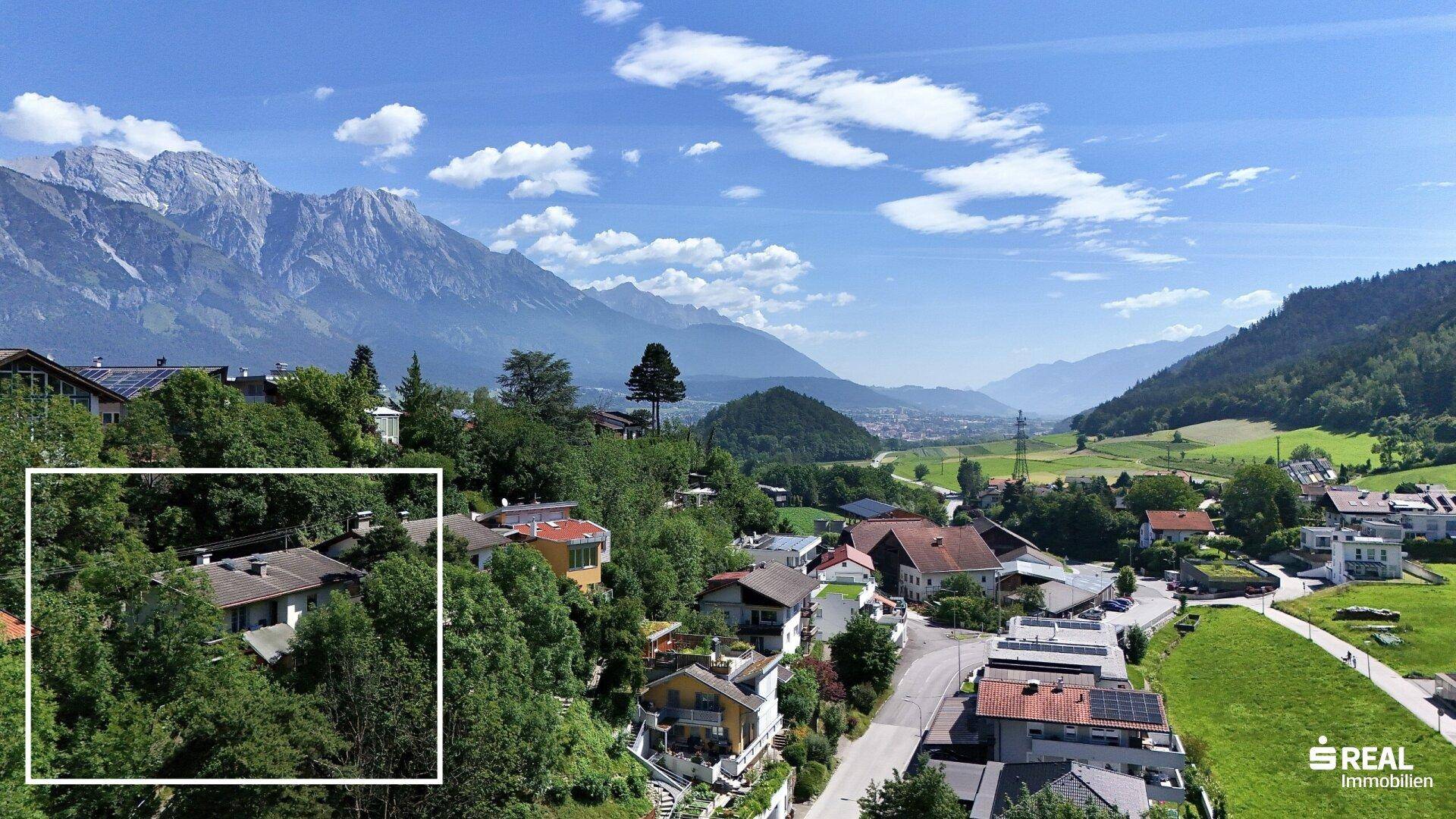 Weitläufiger Blick auf die Berglandschaft und eine Siedlung, mit dem Objekt im Fokus.