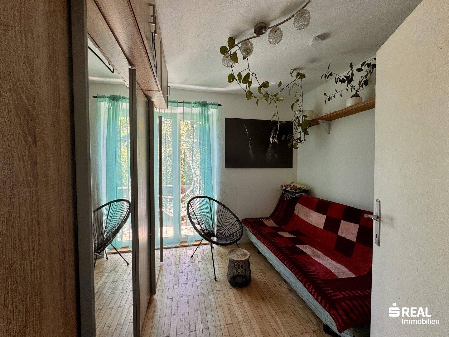 Kleines Zimmer mit Schlafsofa, Spiegelschrank und Zugang zu einem Außenbereich.