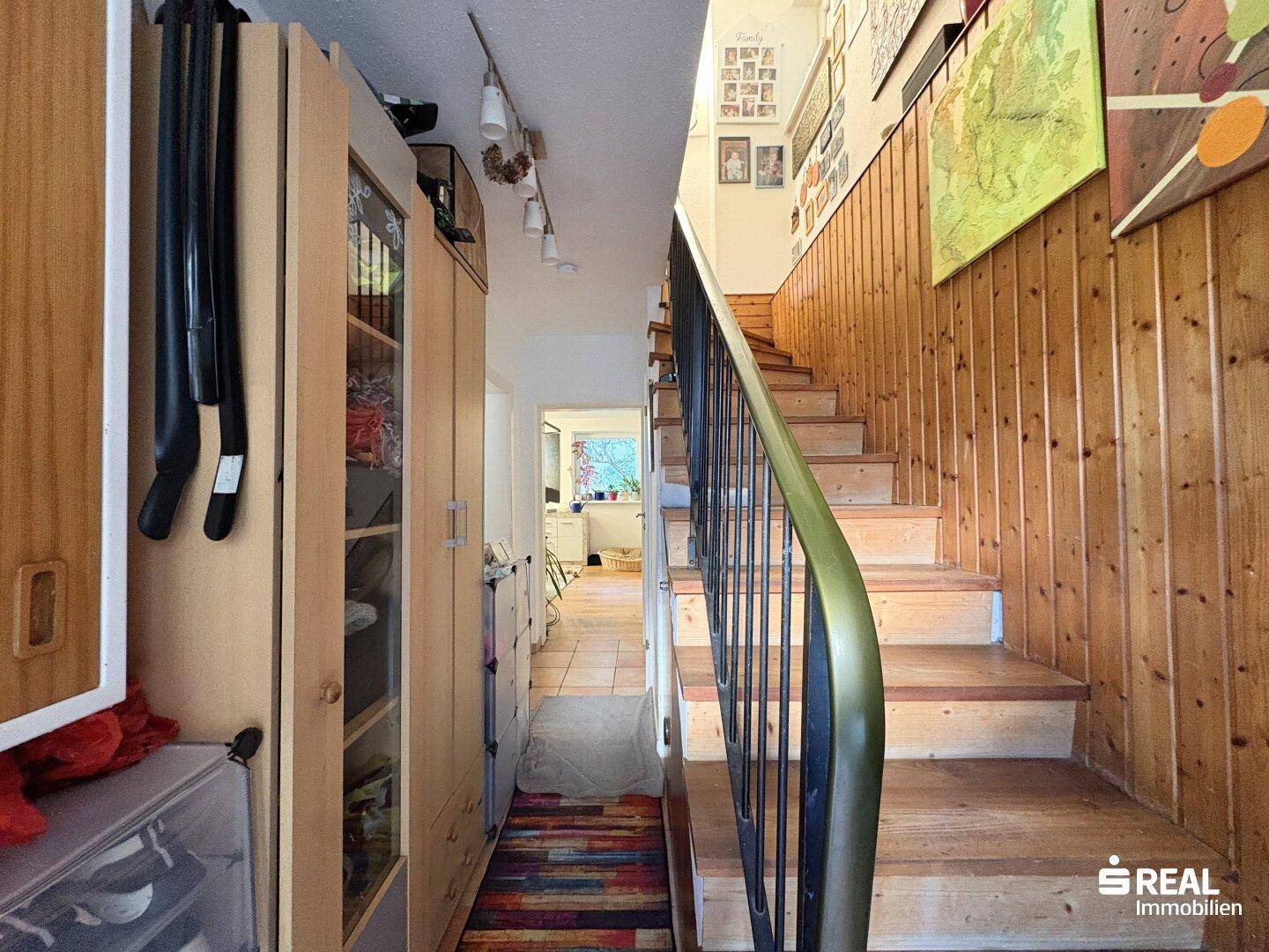 Flur mit Holztreppe, holzvertäfelten Wänden und integrierten Schränken.