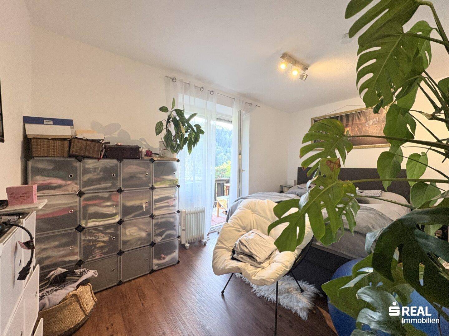 Schlafzimmer mit Balkonzugang, ausgestattet mit einem Doppelbett und praktischen Aufbewahrungsmöbeln.