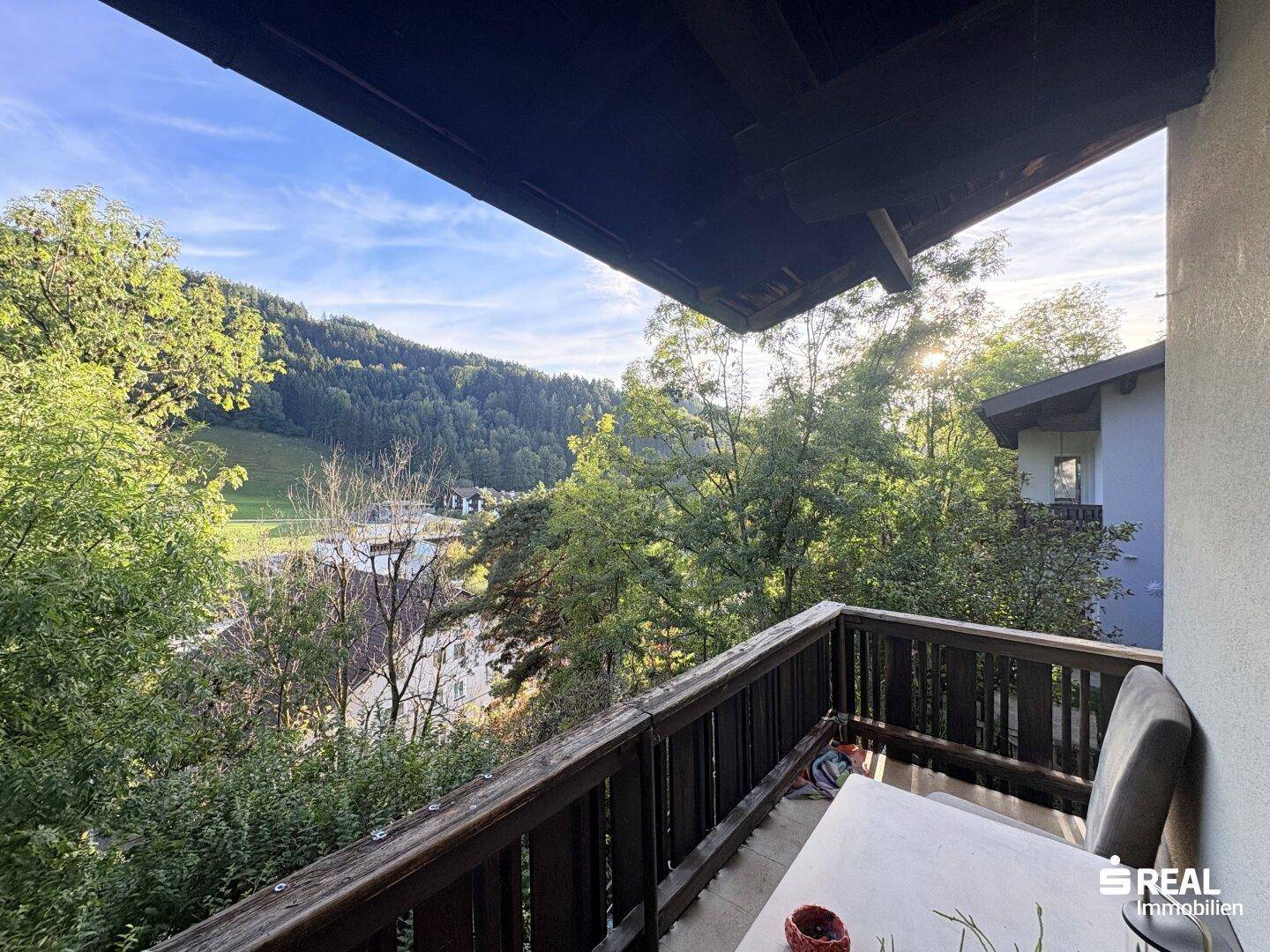 Sonniger Balkon mit Holzbalken und weitem Blick ins Grüne, ideal zum Entspannen.