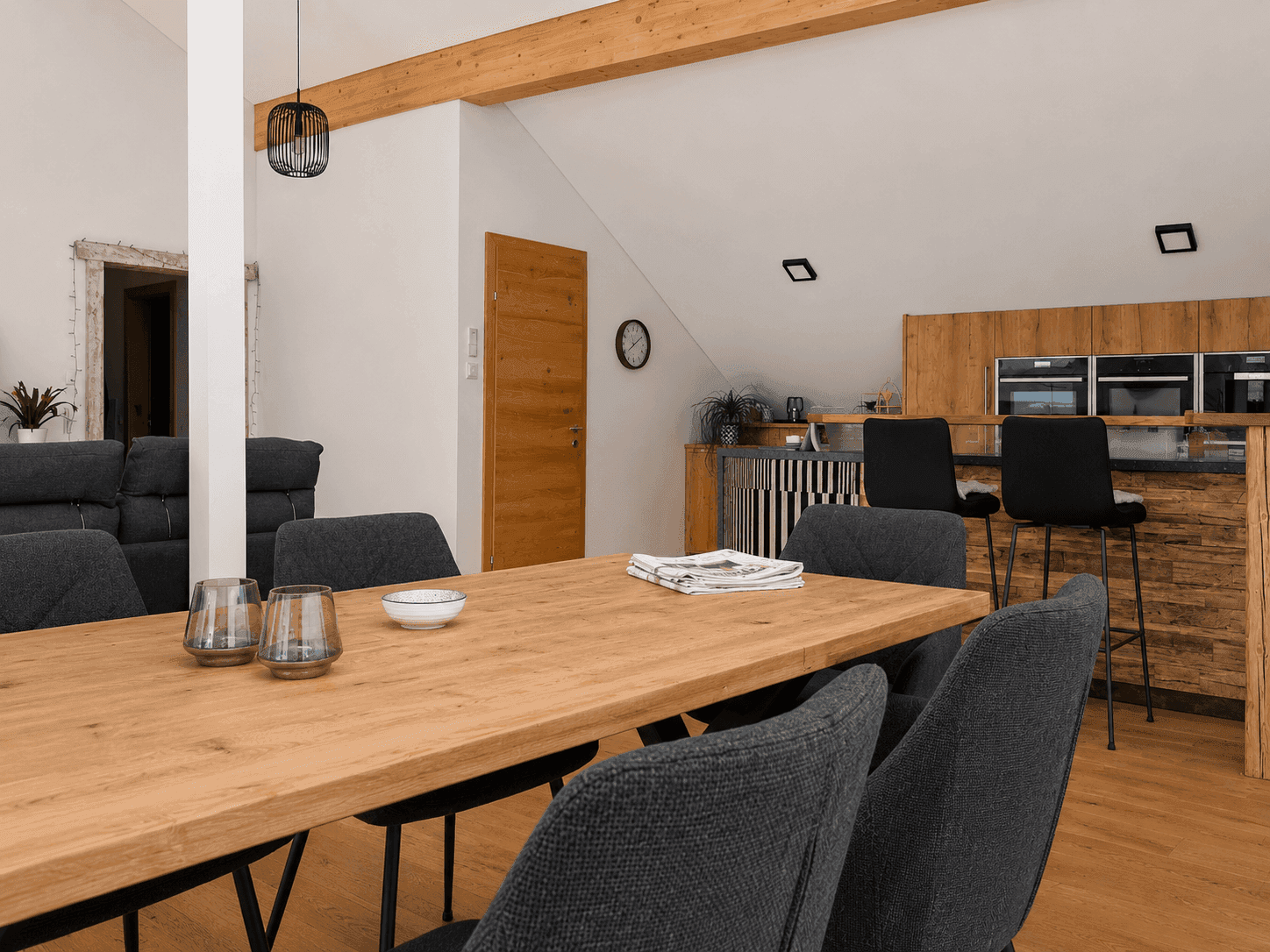 Heller Essbereich mit Holztisch und Blick auf die offene Küche mit modernen Einbaugeräten.