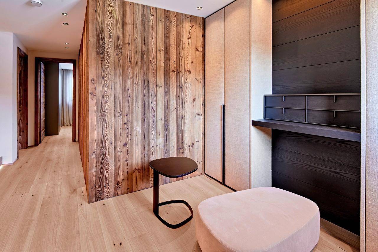 Flur mit Holzwand, integriertem Schminktisch und modernem Hocker.