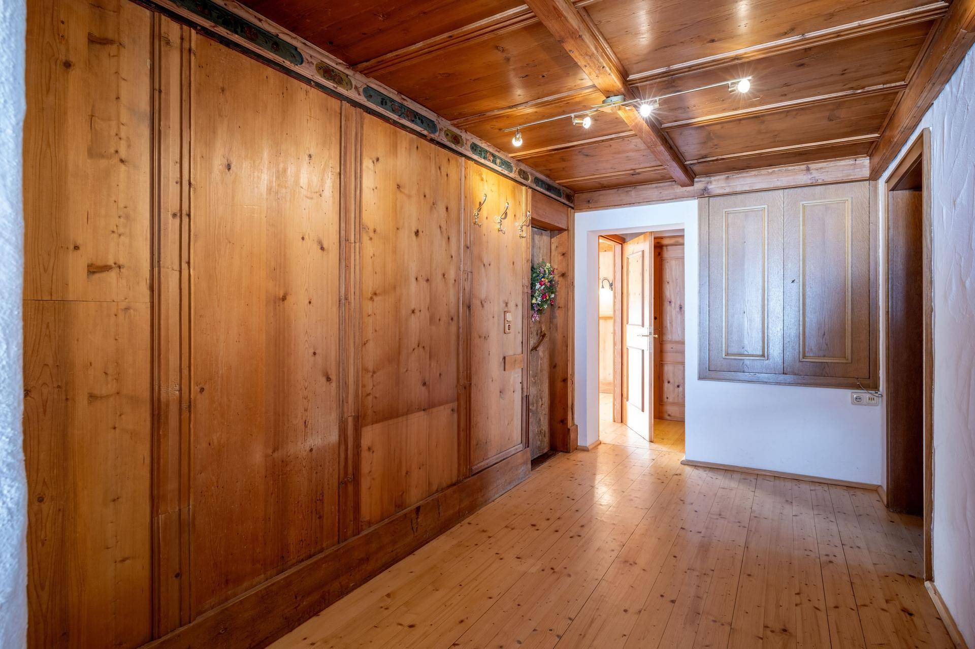 Langer Flur mit Holztäfelung an den Wänden und Decke, der zu weiteren Räumen führt.