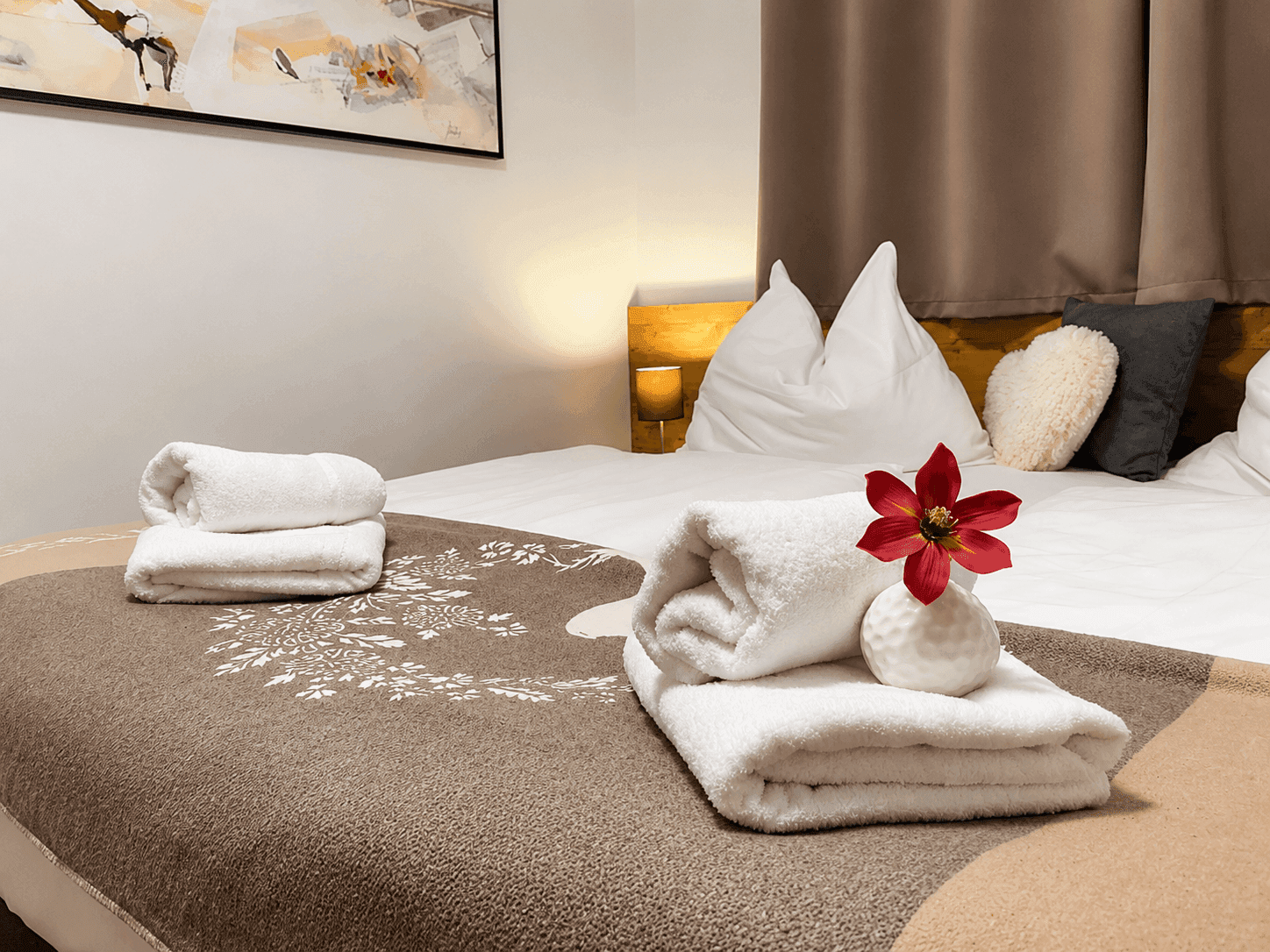 Komfortables Schlafzimmer mit Doppelbett, frischen Handtüchern und warmer Beleuchtung für erholsame Nächte.