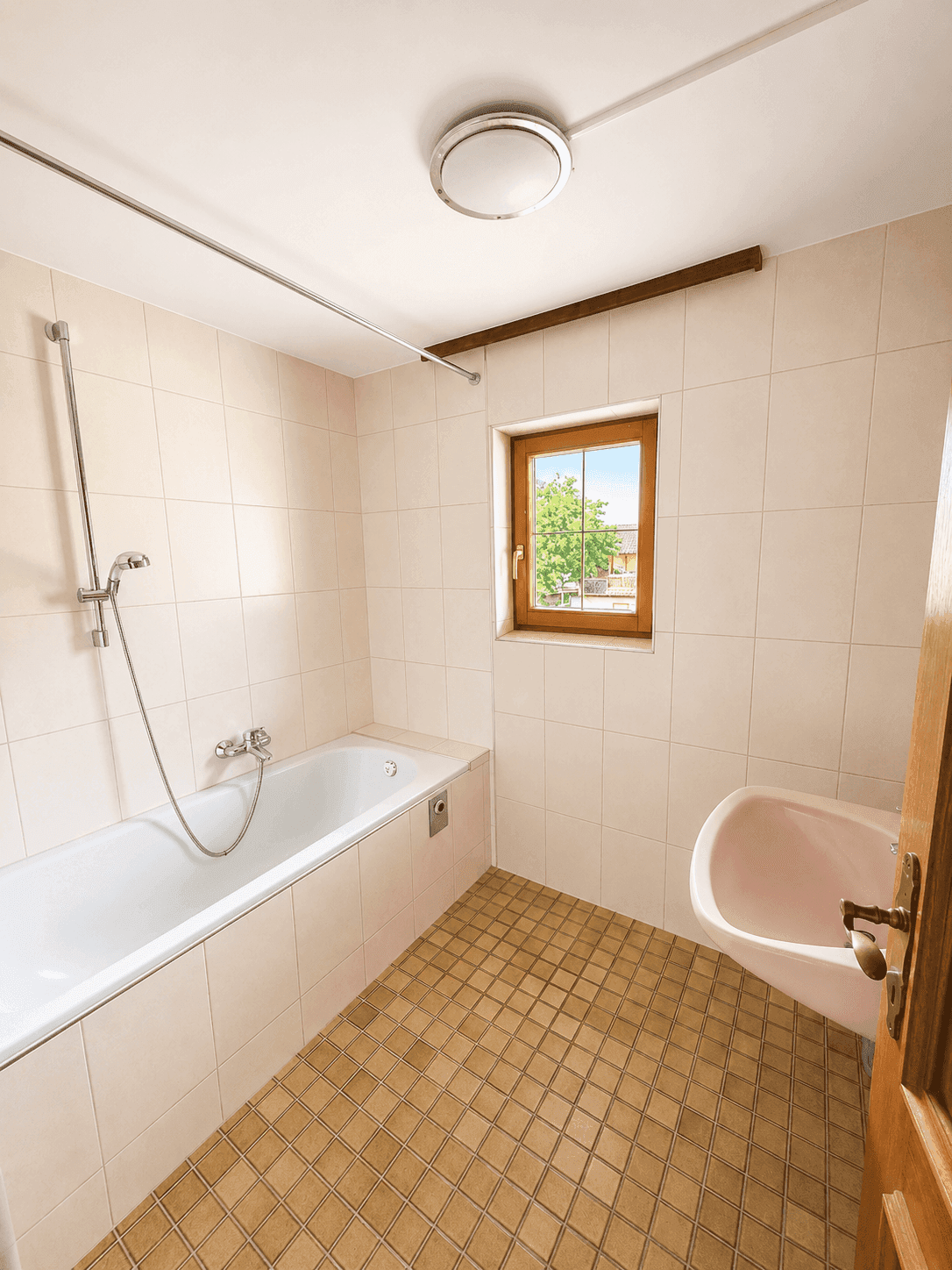 Funktionales Badezimmer mit Badewanne, Waschbecken und Fenster für Tageslicht.
