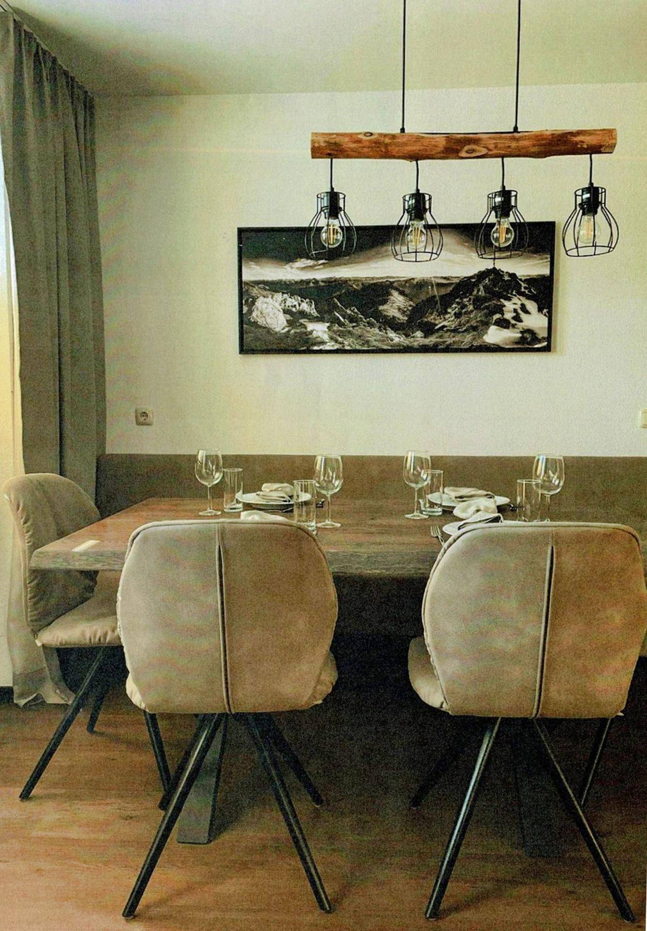 Moderner Essbereich mit Holztisch, bequemen Stühlen und rustikaler Deckenleuchte.