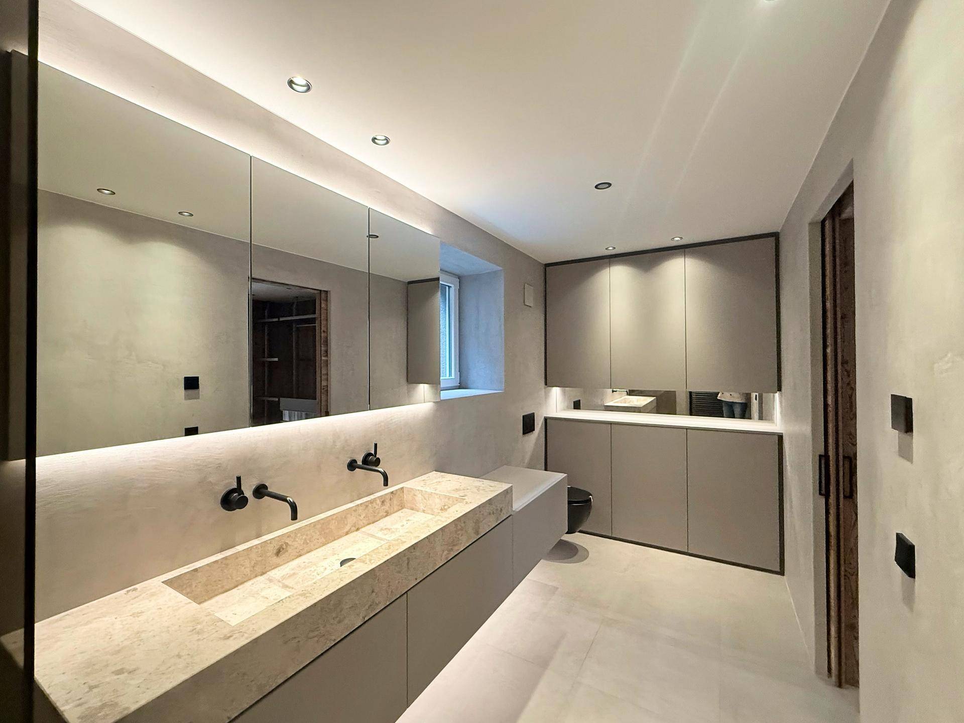 Modernes Badezimmer mit Doppelwaschbecken, Spiegelschrank und indirekter Beleuchtung, elegant und funktional.