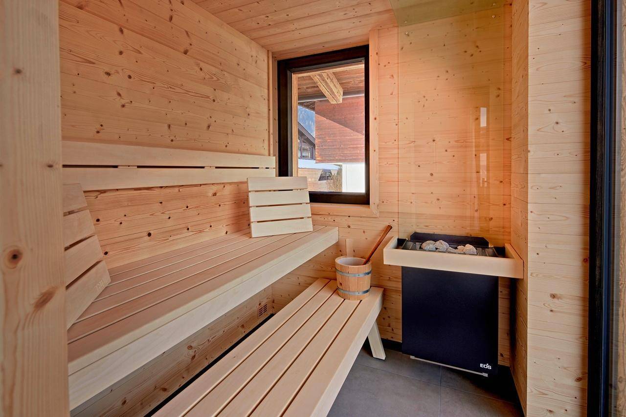 Private Sauna mit Holzverkleidung, Sitzbänken und Ofen für Entspannung.