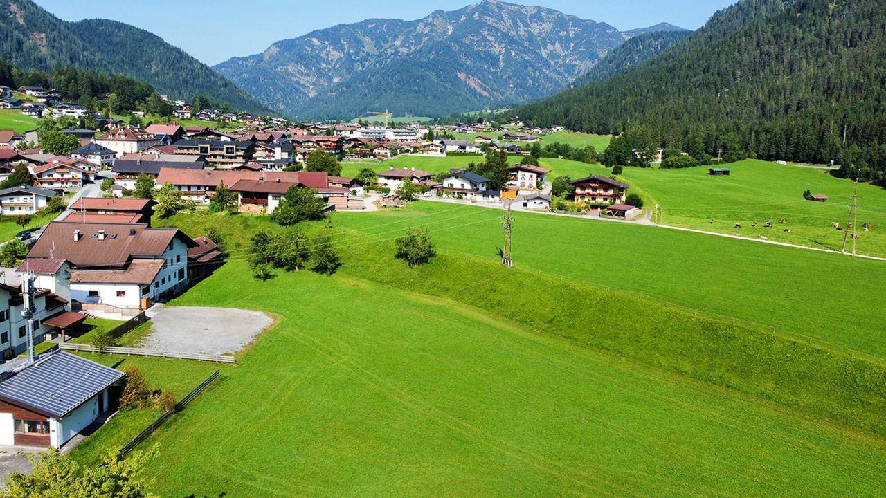 Weitläufige grüne Landschaft mit Häusern und Bergen im Hintergrund, bietet eine idyllische Umgebung.