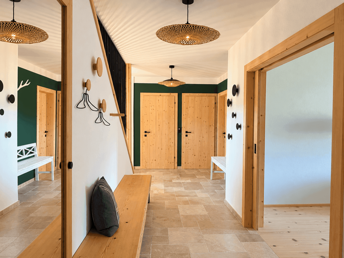 Heller Eingangsbereich mit Fliesenboden, Holzdetails und Garderobe im alpinen Stil.