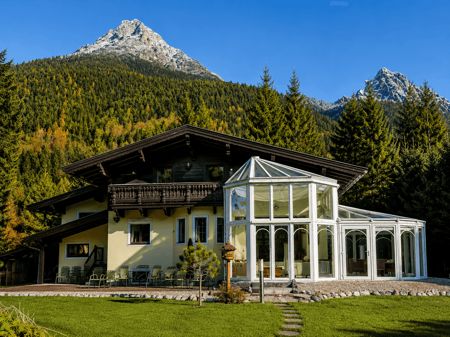 Charmantes Chalet mit Wintergarten und Bergblick, eingebettet in eine malerische Alpenlandschaft.