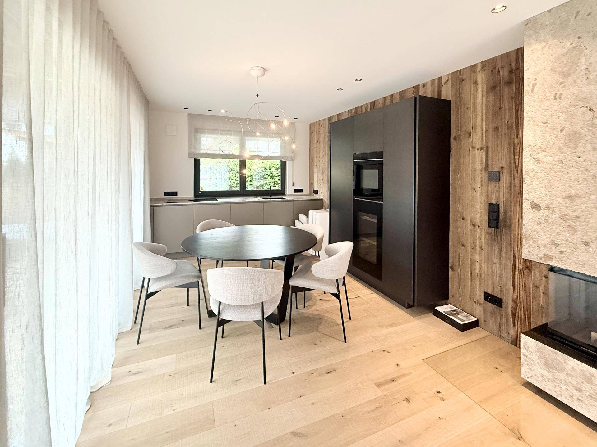 Moderne Küche mit dunklen Schränken, Essbereich und Holzboden, perfekt für gesellige Runden.
