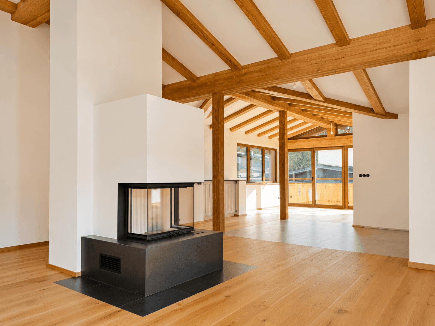 Helles Wohnzimmer mit modernem Kamin, sichtbaren Holzbalken und Eichenparkettboden.