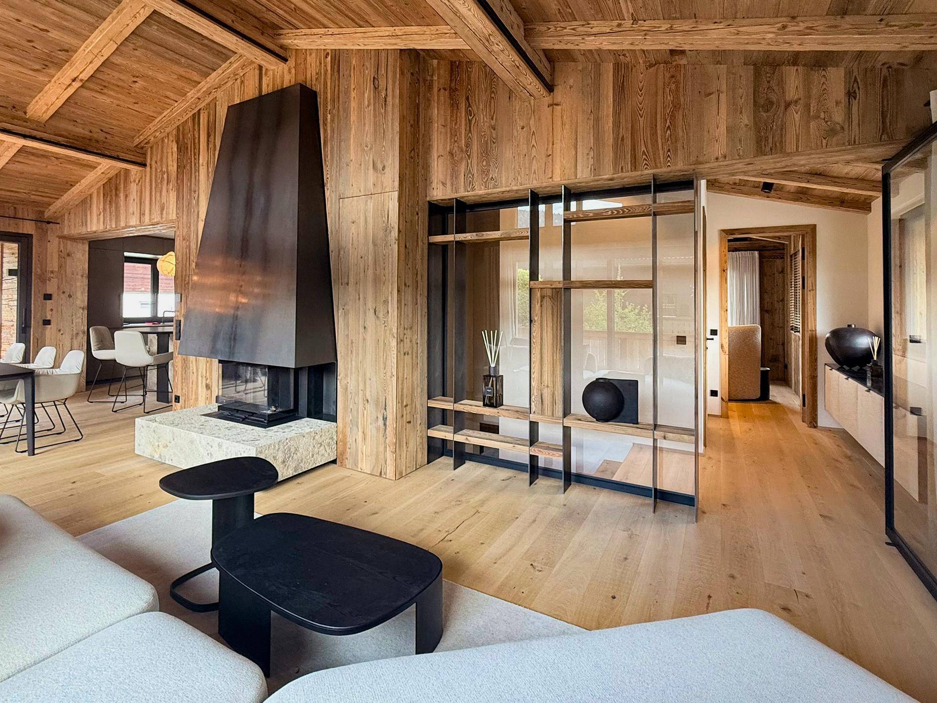 Heller Wohnbereich mit modernem Kamin, Holzwänden und offenem Regal.