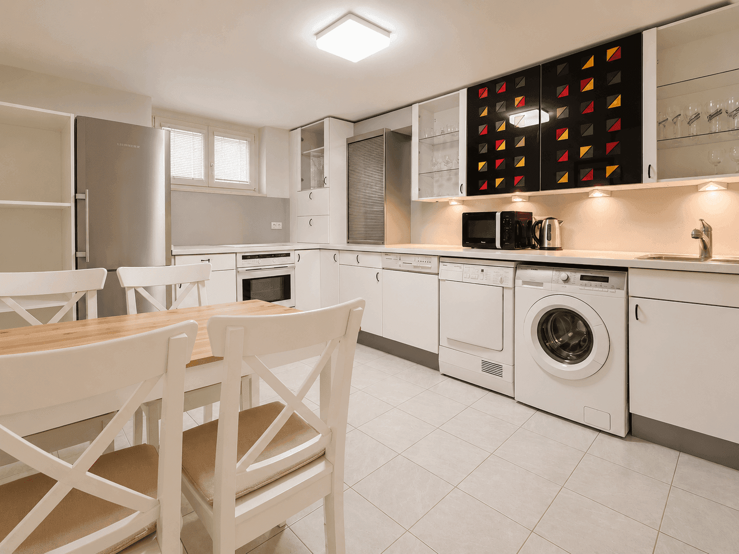 Funktionale Waschküche mit Waschmaschine, Trockner, Kühlschrank und Essbereich.