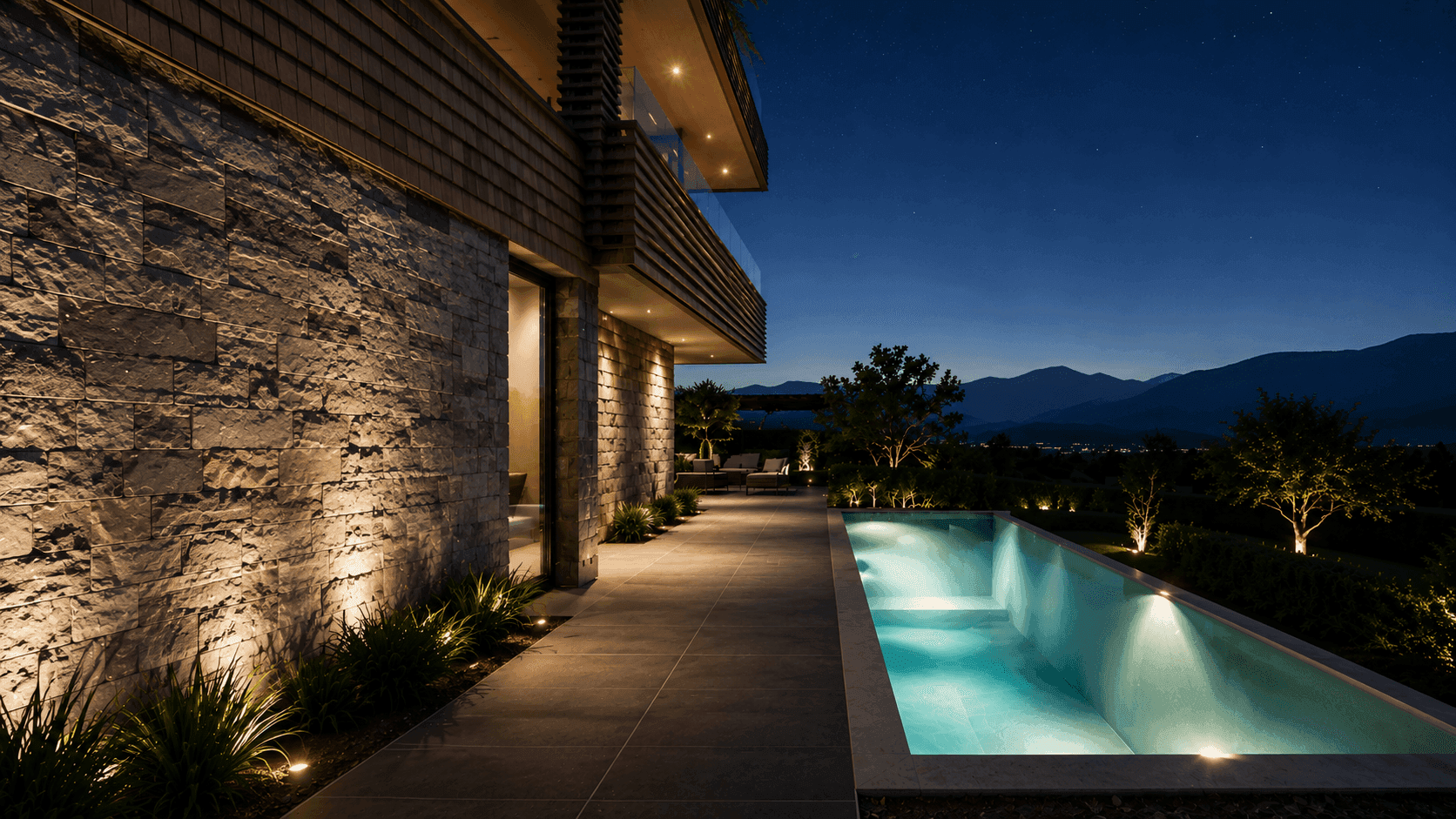 Moderne Villa bei Nacht mit beleuchtetem Pool, Steinfassade und Bergblick unter klarem Sternenhimmel.