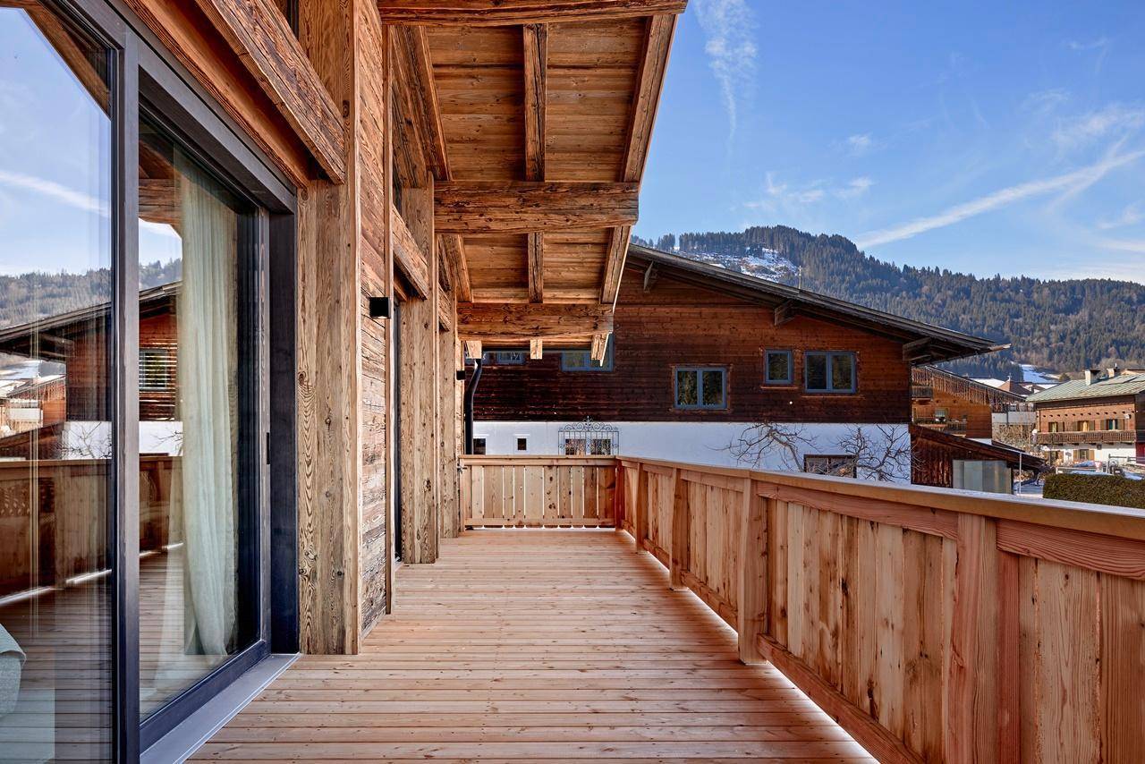 Langer Holzbalkon mit Blick auf die umliegende Berglandschaft und andere Chalets.