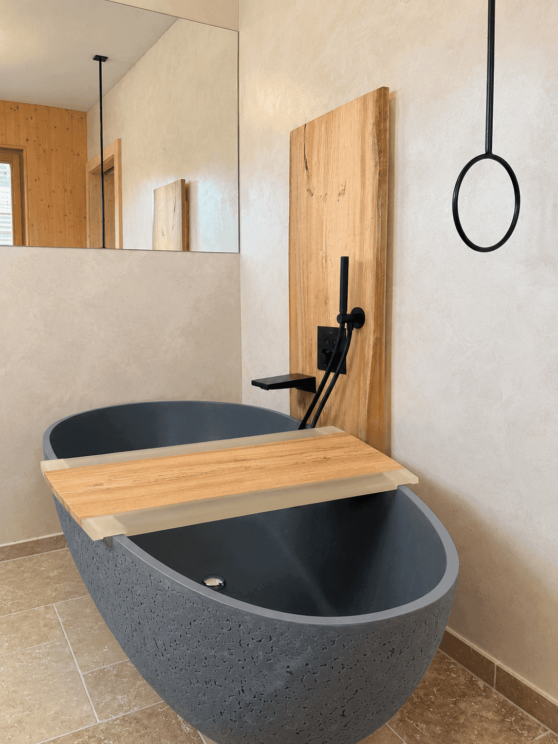 Elegante freistehende Badewanne mit Holzablage und modernen schwarzen Armaturen.
