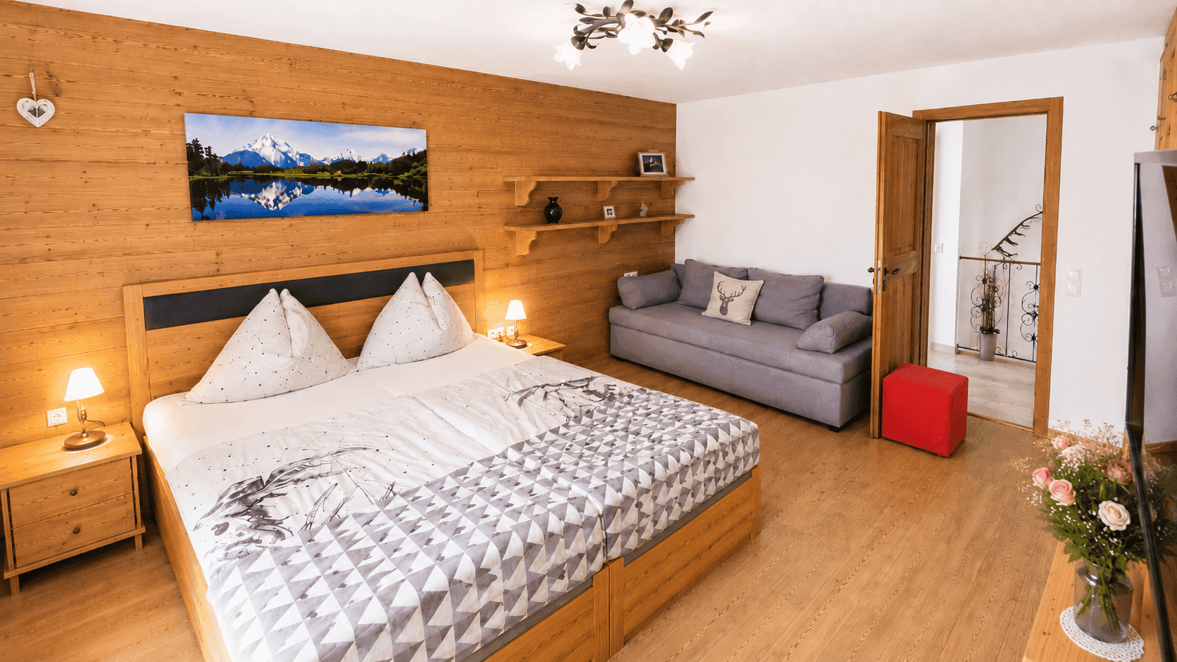Helles Schlafzimmer mit Holzwand, Doppelbett und Sofa, bietet einen ruhigen Rückzugsort.
