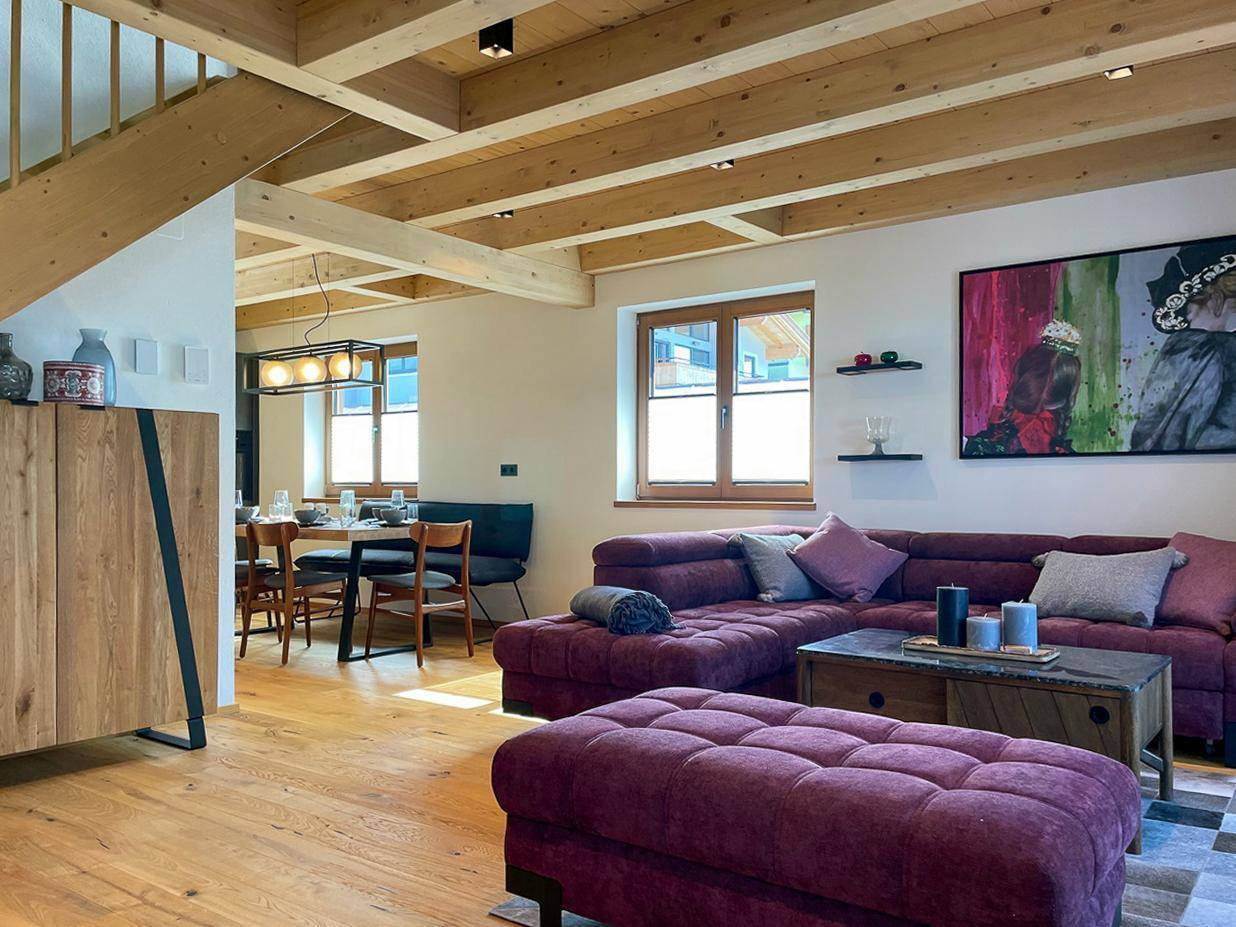 Geräumiger Wohn- und Essbereich mit Holzbalkendecke, Parkettboden und gemütlichem Sofa.