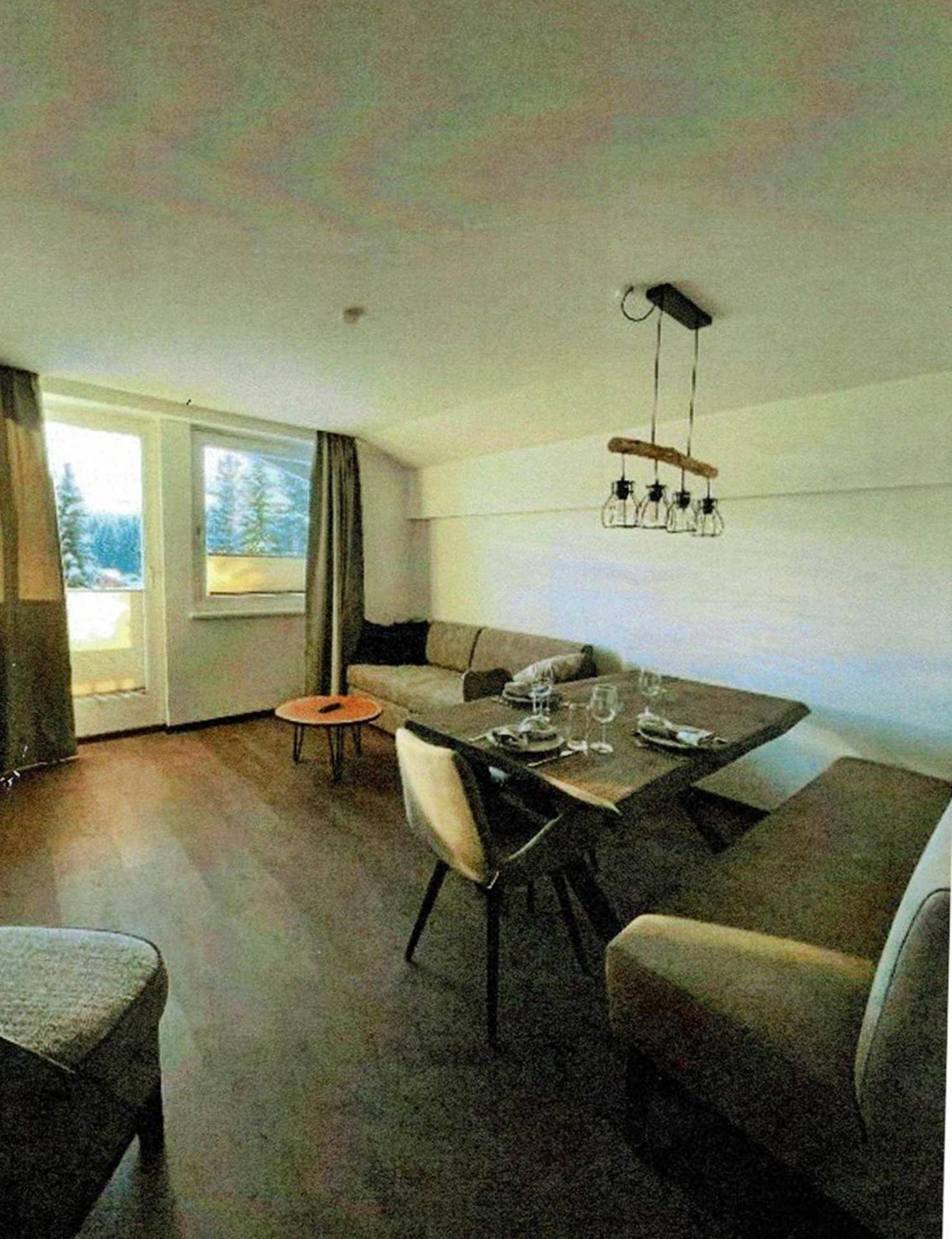 Heller Wohn-Essbereich mit Holzboden, gemütlichem Sofa und Zugang zum Balkon.