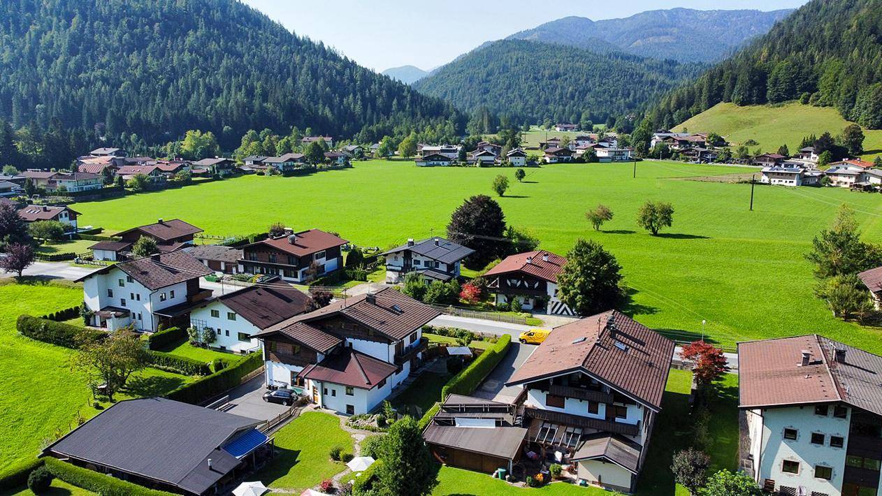 Luftaufnahme einer ländlichen Siedlung mit vielen Häusern und grünen Wiesen, eingebettet in die Natur.